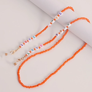 Detail der orangefarbenen Perlenkette für Brillen mit LOVE-Buchstaben und Goldkarabiner