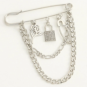Detail of silver rose pendant and rhinestone padlock on multi-layer punk chain brooch