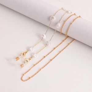 Detail van gouden brillenketting met witte parels en karabijnsluitingen op kolommen
