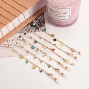 Detail of five golden glasses chains with colorful enamel charms on aesthetic background