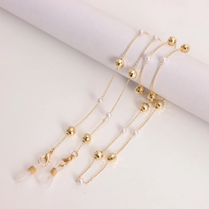 Chaîne de lunettes dorée avec perles blanches et boules facettées sur support blanc