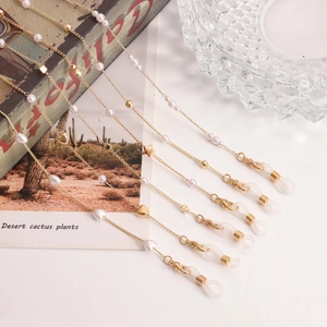 Close-up of golden spectacle chains with pearls and hearts on a vintage backdrop