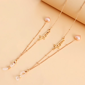 Elegant gold glasses chain with pink heart charms and LOVE lettering on pink background