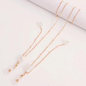 Detail showing golden eyewear chain with milky white beads and silicone loop connectors