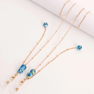 Detail of golden metal glasses chain with blue marble stone beads and silicone loops