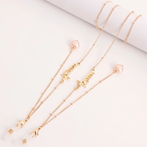 Detail of gold eyewear chain with pink heart pearls and I Love You metal bar pendant
