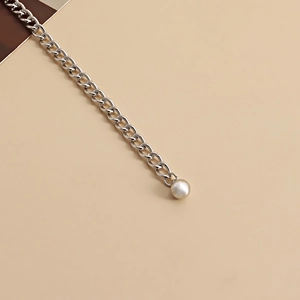 Détail de la chaîne en métal argenté à double couche avec une perle décorative