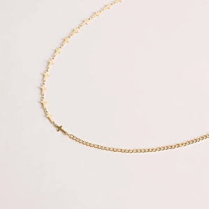 Détail d'une chaîne de taille dorée élégante avec mini croix sur une ceinture simple à maillons