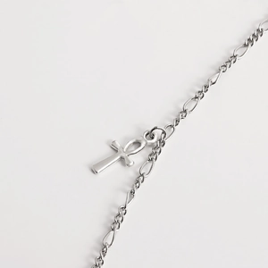 Macro shot of silver Ankh pendant with polished metal Figaro chain details