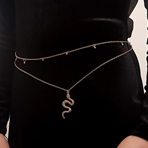 Détail d'une chaîne de taille dorée à double rang avec pendentif serpent sur robe