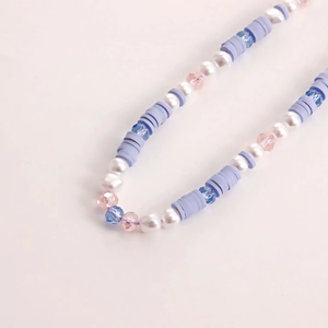 Detailed macro shot of handmade purple clay beads with pearls and crystal glass beads