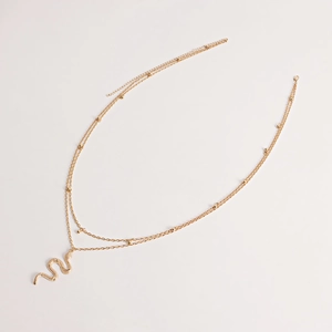Détail de la chaîne de taille dorée à double rang avec pendentif serpent et perles