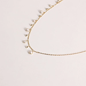 Detailed view of gold chain belt with faux pearls and sparkling zircon tassel accents