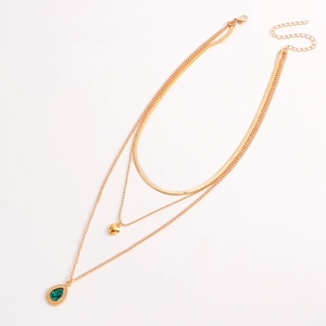 Detail van gouden gelaagde slangketting met groene agaat en hartvormige hangers