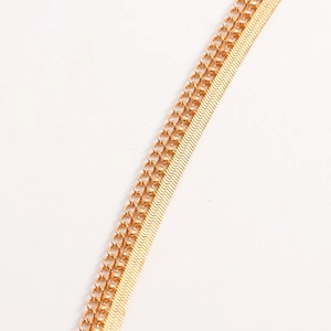 Detail van gelaagde gouden visgraatketting en kralenketting met luxe metalen glans