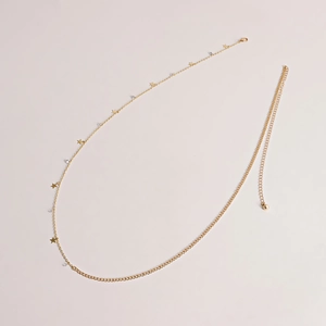 Detail view of gold star charms and crystal beads on a metal waist chain with lobster clasp