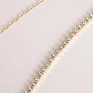 Macro detail of multi-layer waist chain featuring gold claw chain and crystal rhinestones