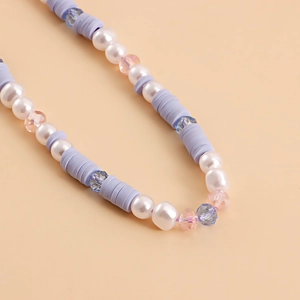 Detailed close-up of purple heishi beads and faux pearl charms on a phone lanyard