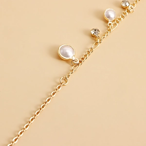 Close-up of elegant gold chain with faux pearls and sparkling cubic zirconia tassels