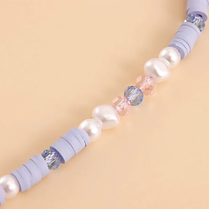 Close-up of purple clay beads and baroque imitation pearls on a mobile phone strap