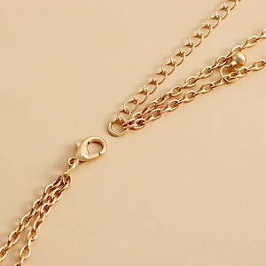 Détail macro d'une ceinture chaîne dorée à double couche avec fermoir et perle ronde
