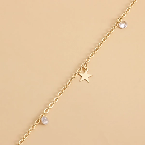 Elegant gold waist chain with star pendant and clear zircon beads on a beige background