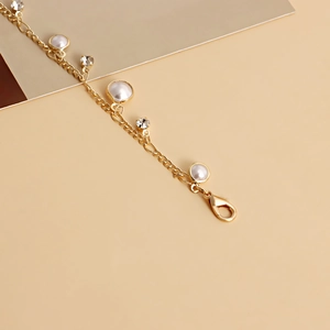 Detail view of golden chain belt featuring elegant pearls and sparkling zircon charms