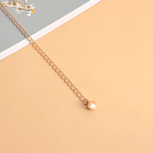 Detail of adjustable gold alloy chain extension with elegant faux pearl drop charm