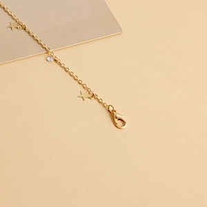 Detailed view of gold metal waist chain featuring star pendants and lobster clasp