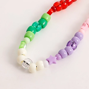 Macro shot of colorful handmade beads including a purple star and small silver bell inside