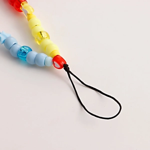 Macro detail of colorful acrylic beads including heart and star shapes on mobile phone strap