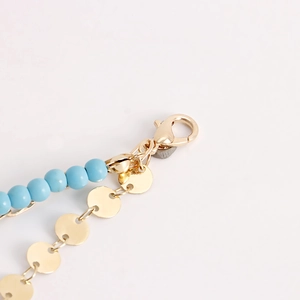 Detail of bohemian gold waist chain featuring blue beads and flat circular metal pendants