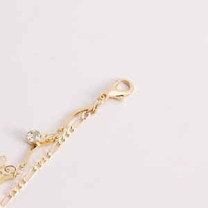 Detailed close-up of golden waist chain with lobster clasp and sparkling zircon stone