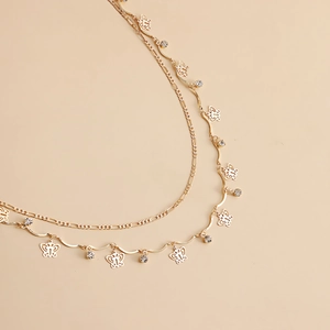 Double-layered golden butterfly tassel chain with acrylic zircon accents on almond background