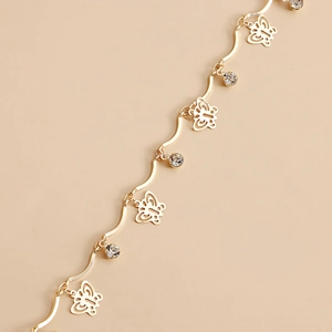 Detailed close-up of golden butterfly waist chain with sparkling crystal charms and wave links