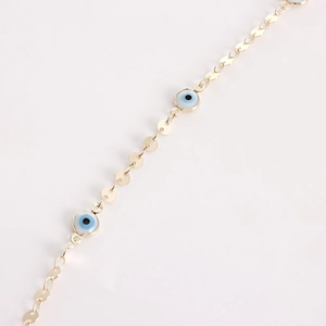 Close-up of golden geometric waist chain featuring blue evil eye enamel charms on white