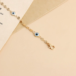 Detailed macro of golden geometric waist chain with blue evil eye charms and clasp