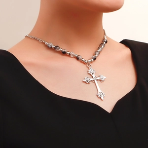 Detailed close-up of a vintage silver cross pendant with layered beads on a necklace