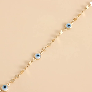 Detailed view of a gold waist chain featuring blue and white enamel evil eye charms