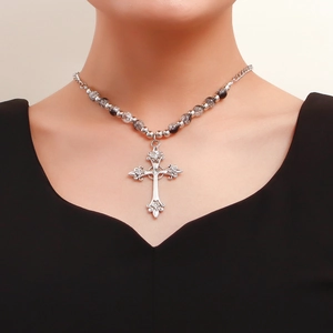Close-up of vintage gothic cross pendant with embossed patterns and beaded chain