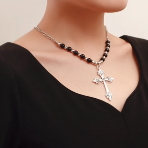 Detail of vintage silver cross pendant with floral engraving on beaded chain necklace