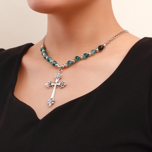 Detail of vintage silver cross pendant with green agate beads on a layered necklace