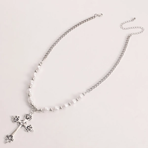 Detail of vintage silver cross pendant with intricate relief and pearl chain necklace