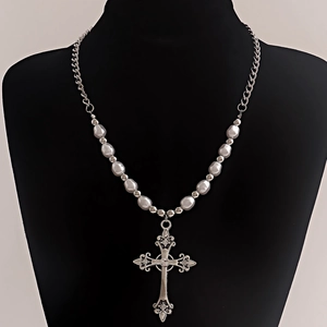 Detail of baroque cross pendant with pearls and metallic chain on a jewelry bust
