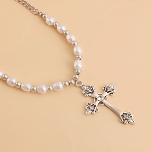 Detail of vintage layered pearl necklace featuring an ornate baroque cross pendant with rhinestones