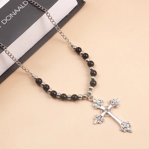 Detailed macro view of vintage cross pendant with fleur-de-lis accents and silver beads