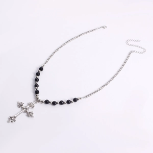Macro view of vintage cross pendant with baroque relief and black bead chain details