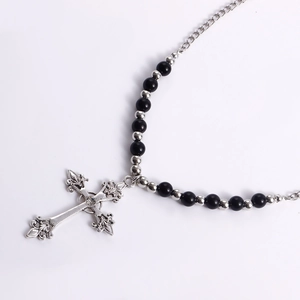 Close-up of vintage engraved silver cross pendant with clear gemstone and black beads