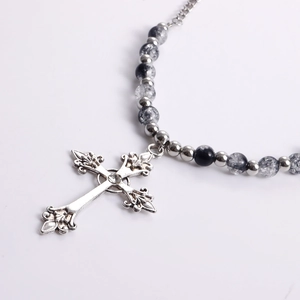 Detail of silver vintage fleur-de-lis cross pendant with mixed black and grey beaded chain