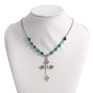 Close-up of vintage cross pendant with turquoise beads on a silver multilayered necklace